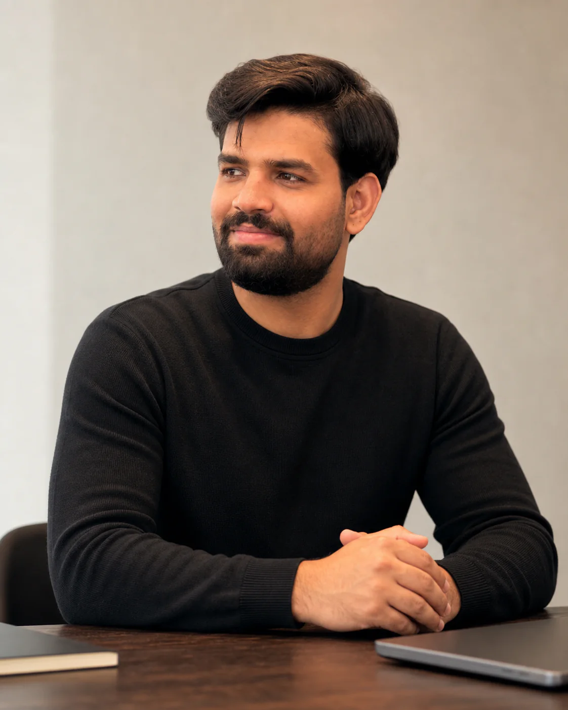 Tanzeel seated at a desk in a black sweater